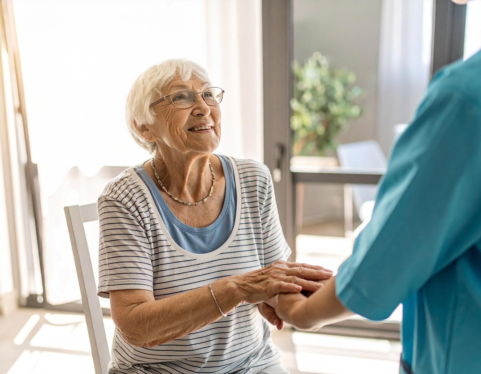 Seniorin hält die Hände einer Pflegekraft