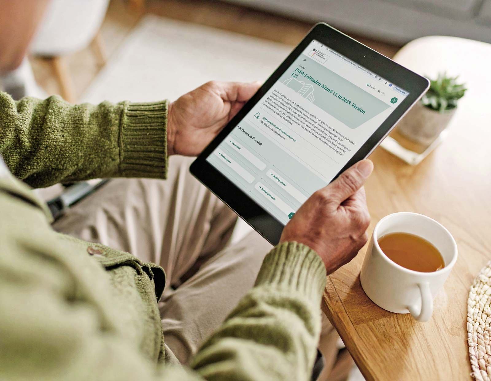 Senior hält Tablet mit DiPA-Leitfaden in den Händen