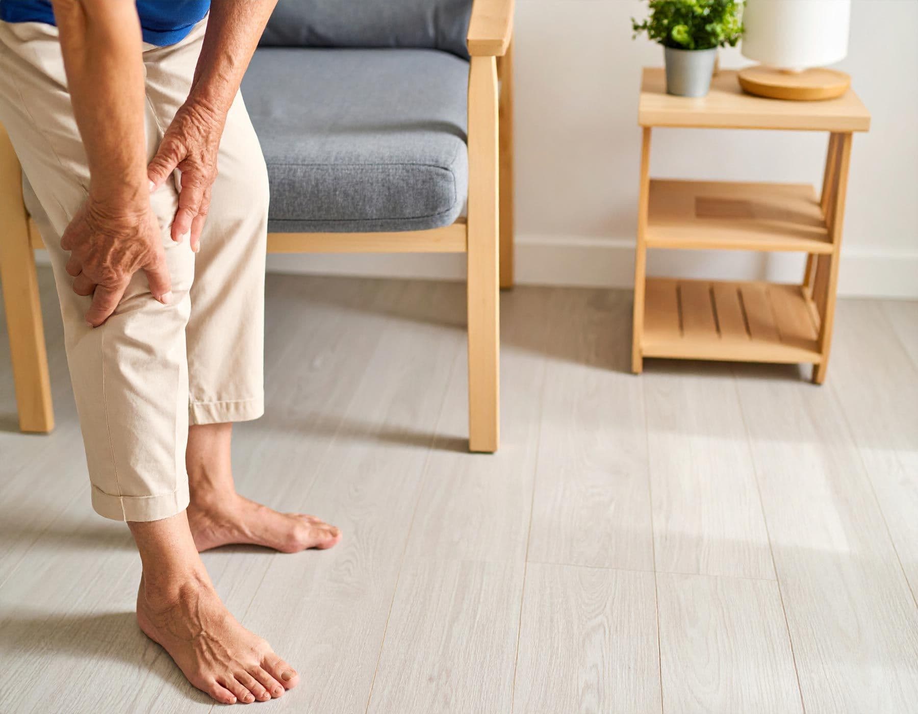 Ältere Person steht und hält schmerzhaft ihr rechtes Knie