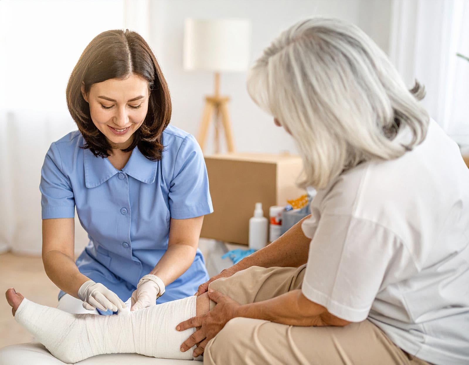 Krankenschwester verbindet das Bein einer Seniorin mit weißem Verband