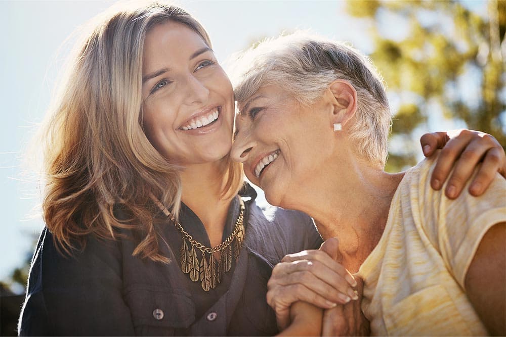 eine Frau umarmt ihre ältere Mutter 