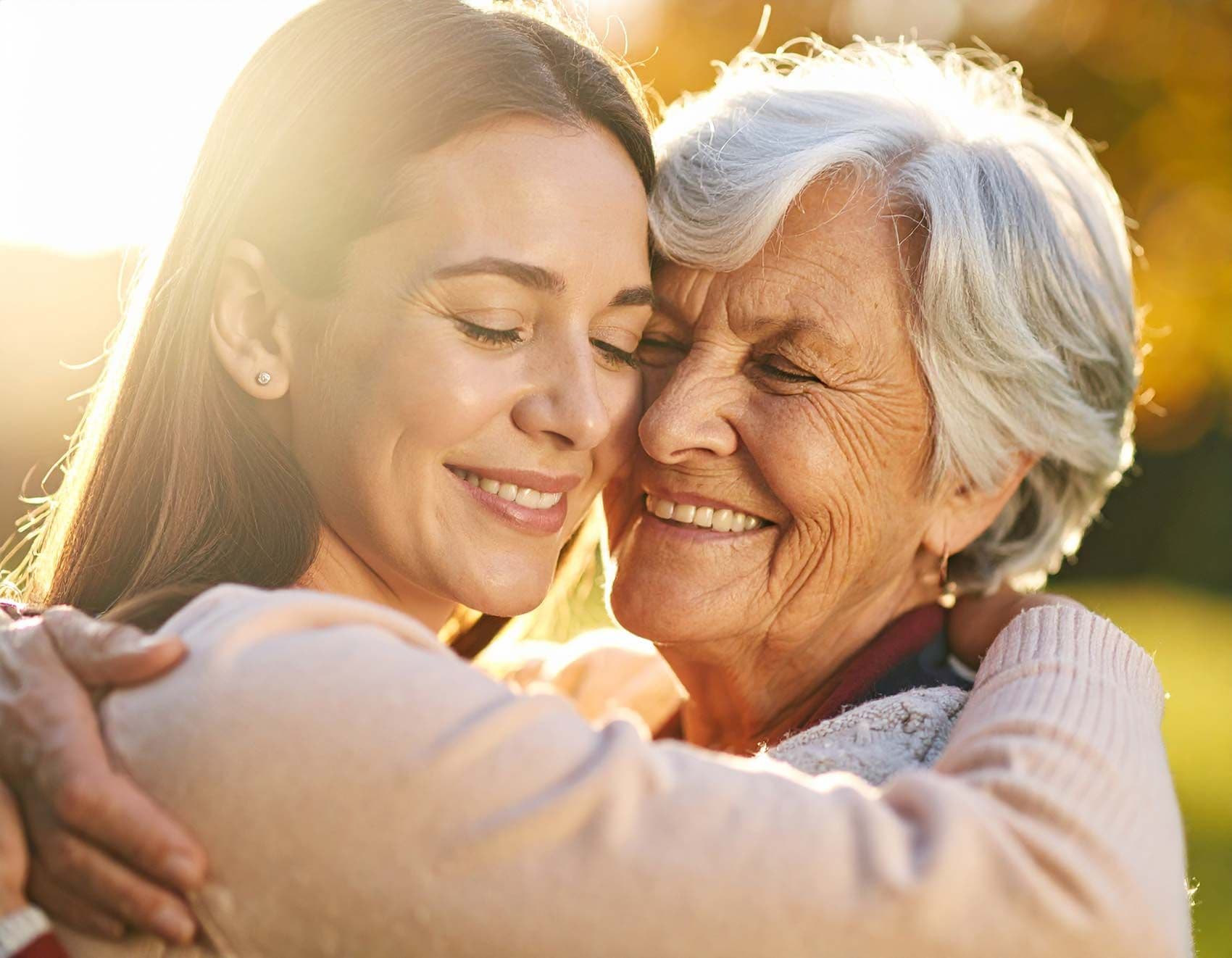 Pflegeperson umarmt Seniorin