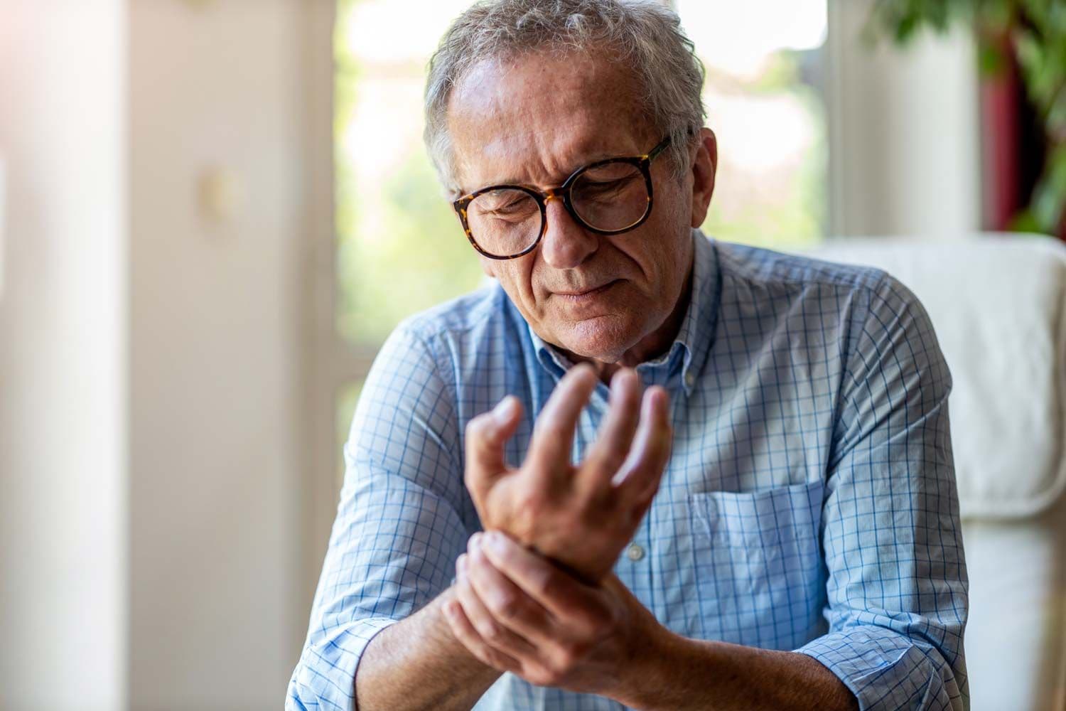 Älterer Mann hält schmerzverzerrt seine Hand