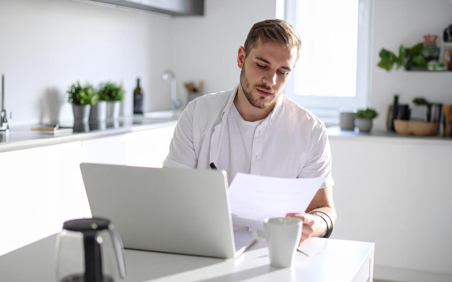 Mann sitzt am Küchentisch, füllt Dokumente aus