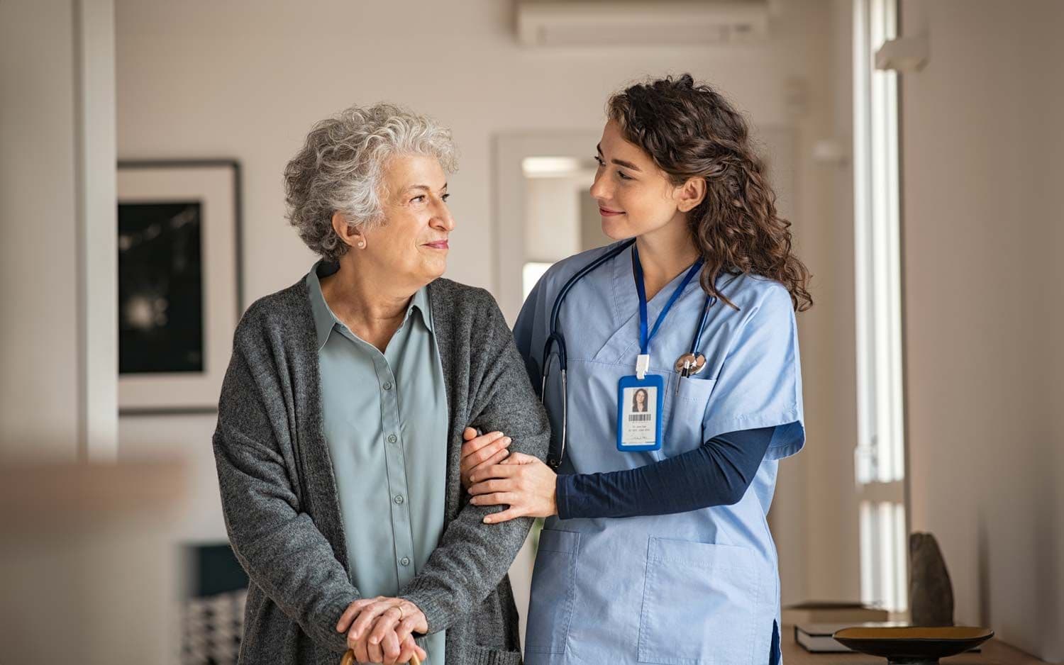 Ältere Frau wird von einer Pflegekraft am Arm gehalten