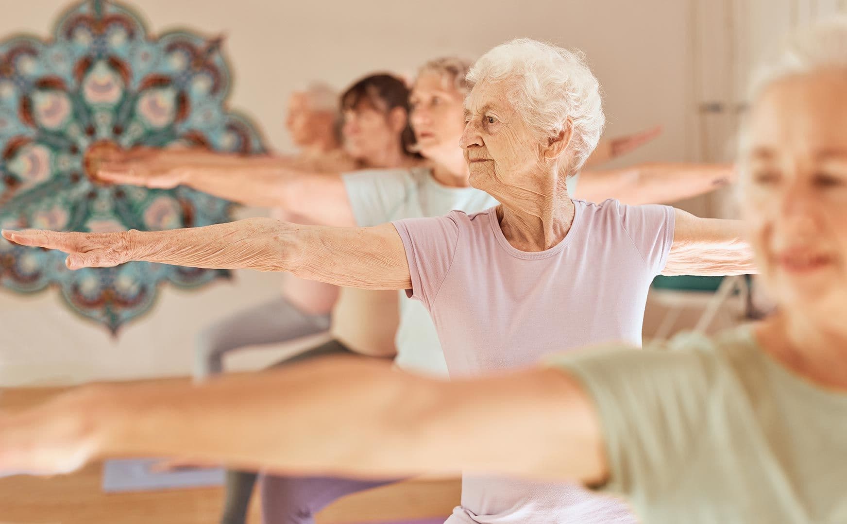 Seniorengruppe macht Yoga-Übung mit ausgestreckten Armen