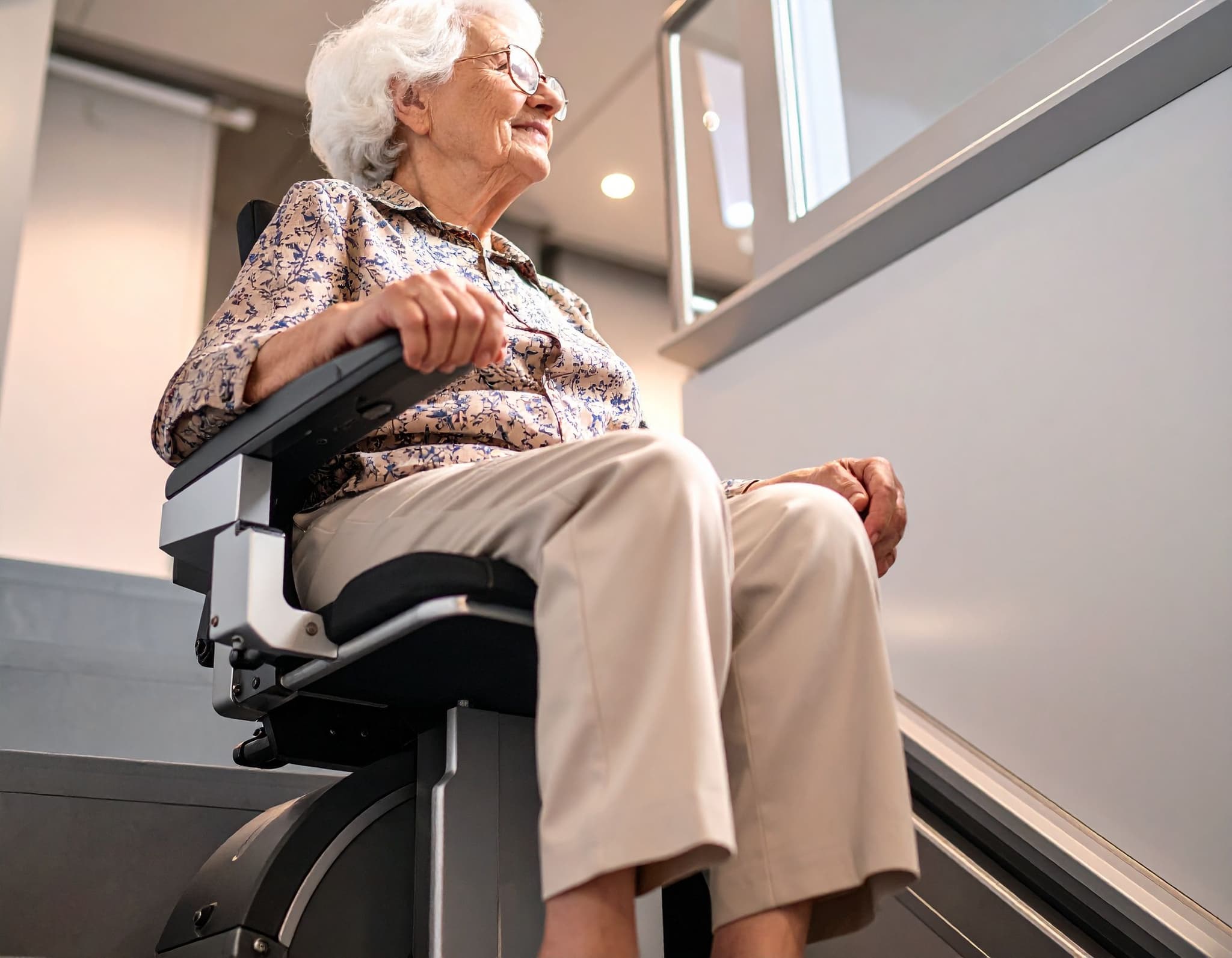 Seniorin sitzt auf einem Treppenlift in einem Haus