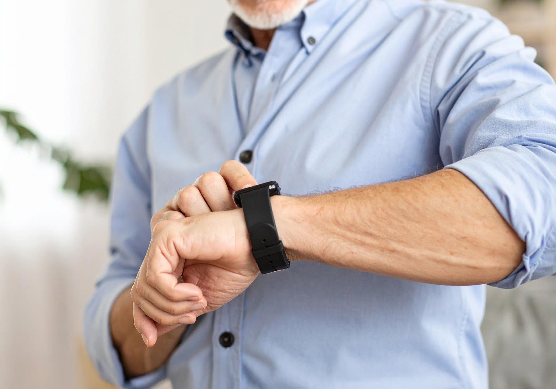 Älterer Mann betrachtet ein Notfallarmband an seinem Handgelenk